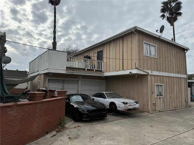 rear view of property featuring a balcony and a garage