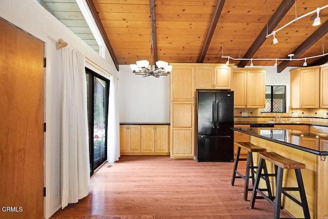 kitchen featuring a breakfast bar area, vaulted ceiling with beams, black fridge, wood ceiling, and light brown cabinets