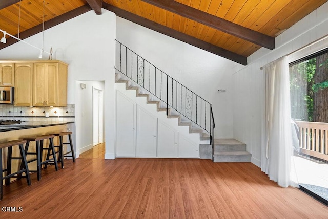 stairs featuring beamed ceiling, wood-type flooring, high vaulted ceiling, and wooden ceiling