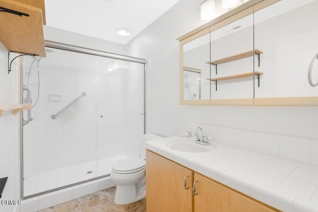 bathroom featuring vanity, a shower with shower door, and toilet