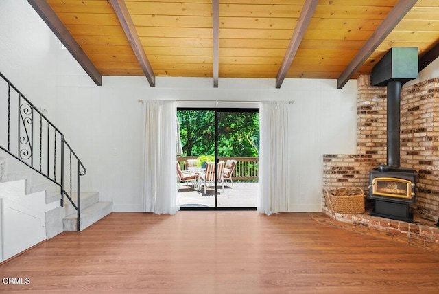 unfurnished living room featuring vaulted ceiling with beams, wooden ceiling, light hardwood / wood-style flooring, and a wood stove