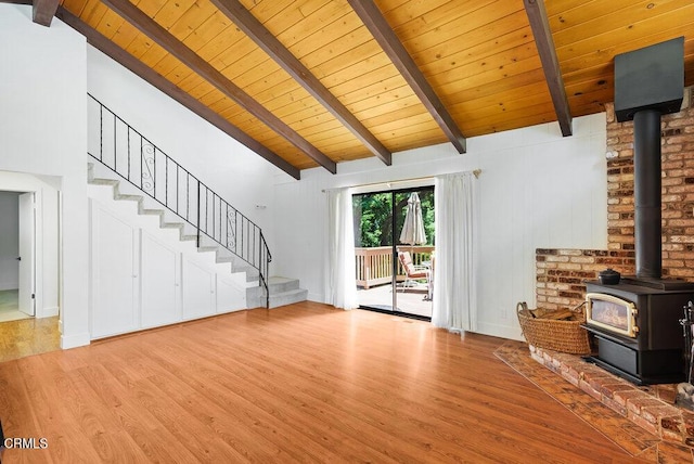 unfurnished living room with beam ceiling, light hardwood / wood-style flooring, wooden ceiling, and a wood stove