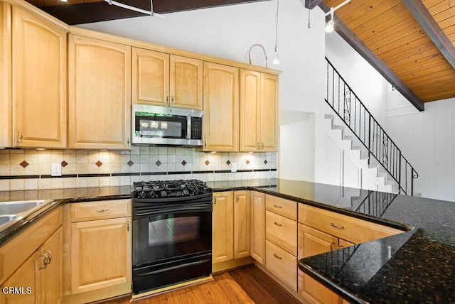 kitchen with hardwood / wood-style flooring, dark stone counters, black gas stove, and light brown cabinets