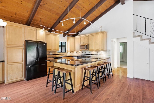 kitchen featuring a kitchen island, black refrigerator, light brown cabinets, and a kitchen breakfast bar