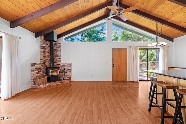 living room featuring wood ceiling, a wood stove, lofted ceiling with beams, ceiling fan with notable chandelier, and light wood-type flooring