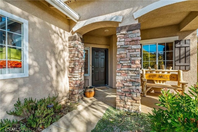 view of exterior entry featuring stone siding and stucco siding