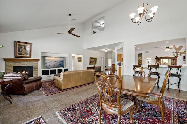 dining room with lofted ceiling, tile patterned flooring, a fireplace, and ceiling fan with notable chandelier