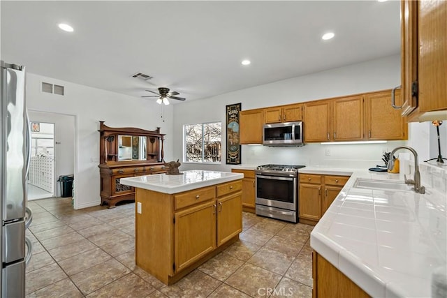 kitchen with appliances with stainless steel finishes, visible vents, a sink, and a kitchen island