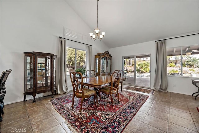 tiled dining space with high vaulted ceiling, a healthy amount of sunlight, a notable chandelier, and baseboards