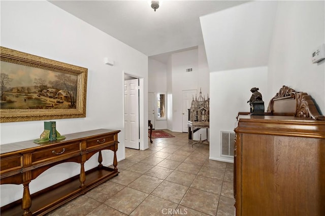 corridor featuring visible vents, baseboards, and tile patterned floors