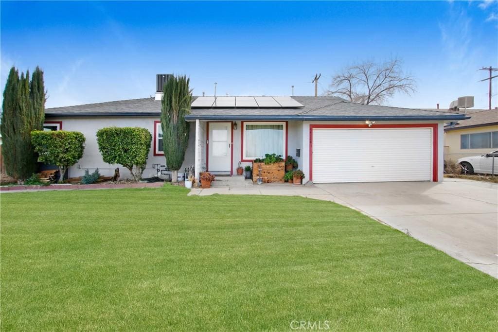 single story home featuring a garage, a front yard, and solar panels