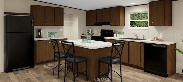 kitchen with under cabinet range hood, light countertops, light wood-type flooring, black appliances, and a sink