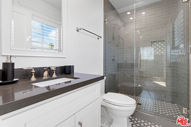 bathroom with toilet, vanity, and a shower with shower door