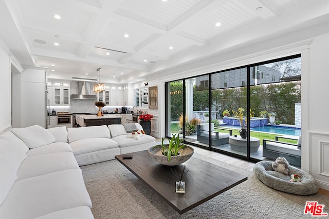 living room featuring coffered ceiling, beam ceiling, wood-type flooring, and a healthy amount of sunlight