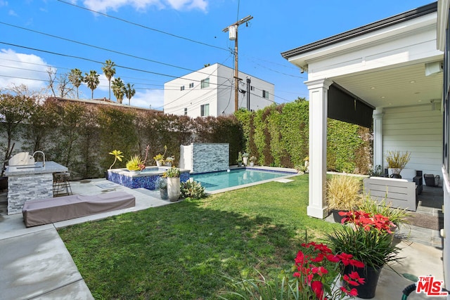 view of yard with a swimming pool with hot tub, exterior kitchen, a bar, and a patio