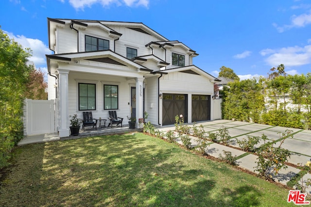 view of front of home featuring a porch, a garage, and a front lawn