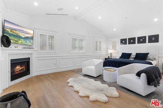 bedroom featuring a fireplace, light hardwood / wood-style flooring, and vaulted ceiling with beams