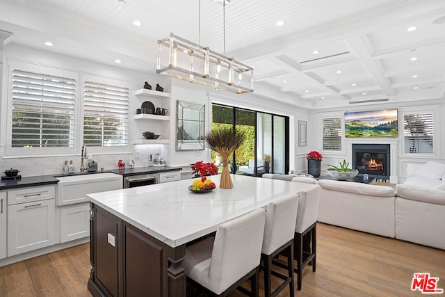 kitchen featuring pendant lighting, dark stone countertops, coffered ceiling, light hardwood / wood-style floors, and white cabinets