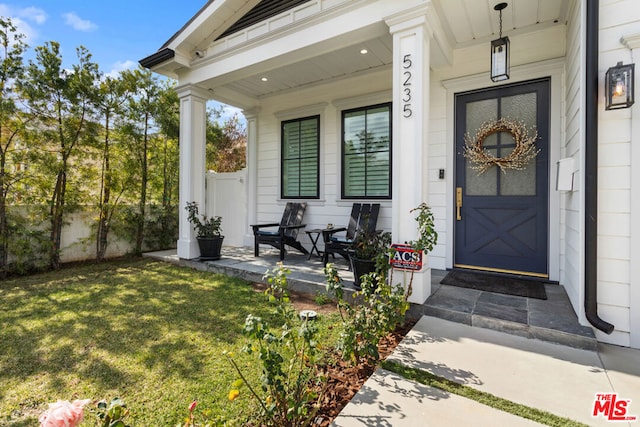 property entrance featuring a yard and covered porch