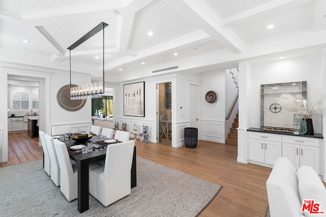 dining room featuring crown molding, coffered ceiling, beam ceiling, and light hardwood / wood-style flooring