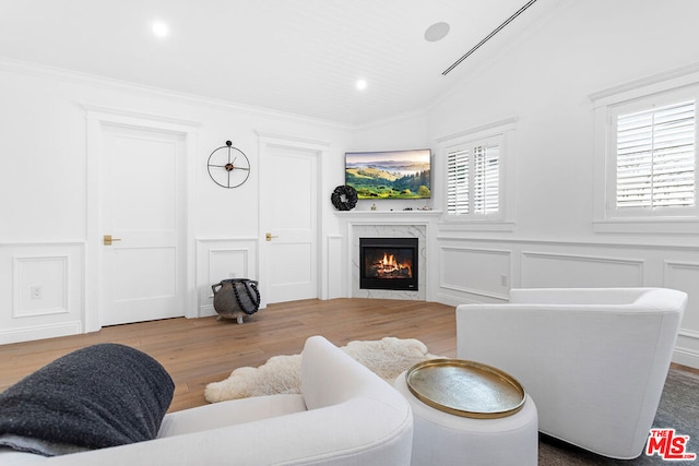 living room featuring crown molding, light wood-type flooring, a wealth of natural light, and a high end fireplace