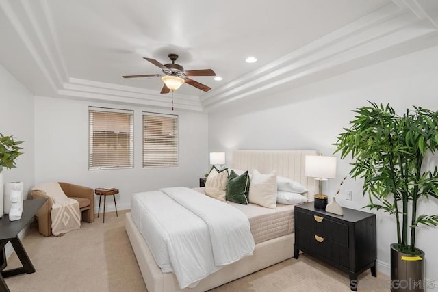 bedroom featuring light colored carpet, a raised ceiling, and ceiling fan