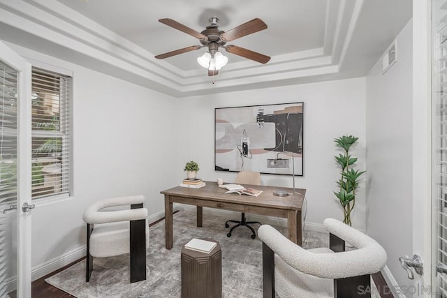 office space featuring hardwood / wood-style floors, a tray ceiling, and ceiling fan