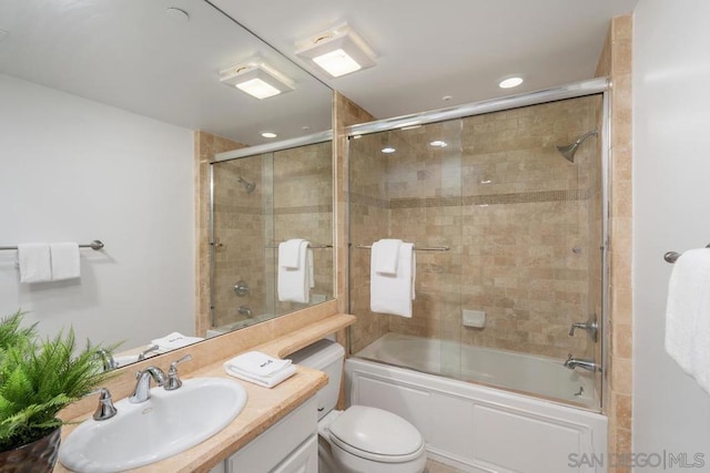 full bathroom featuring vanity, bath / shower combo with glass door, and toilet