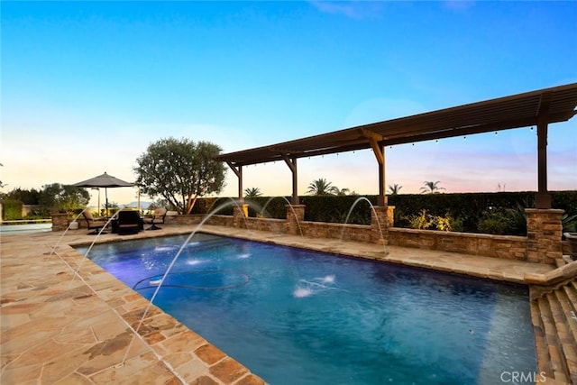 pool at dusk featuring a patio area and pool water feature