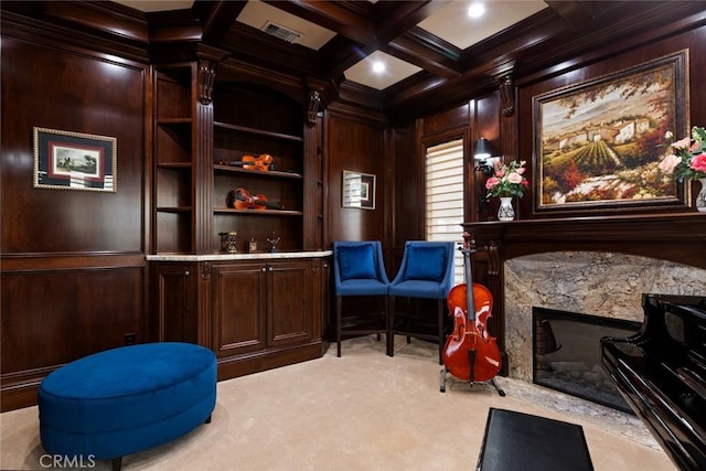 living area with beam ceiling, coffered ceiling, a high end fireplace, light carpet, and wood walls