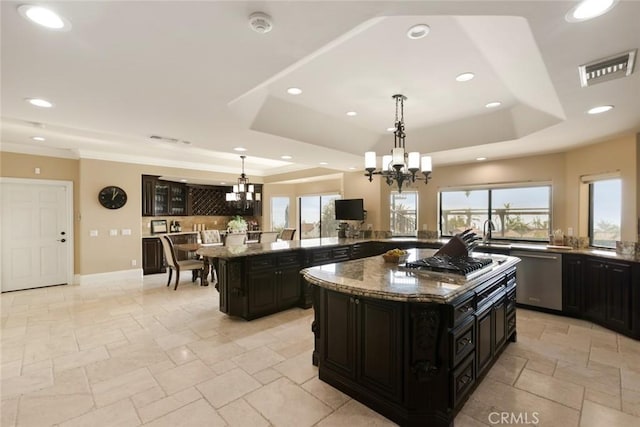 kitchen with decorative light fixtures, a raised ceiling, a chandelier, and a kitchen island