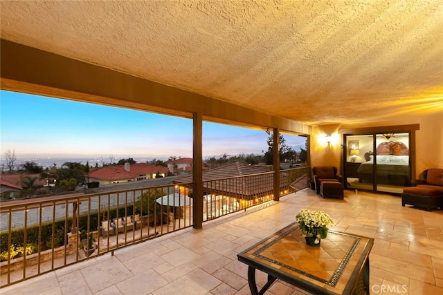 patio terrace at dusk featuring a balcony