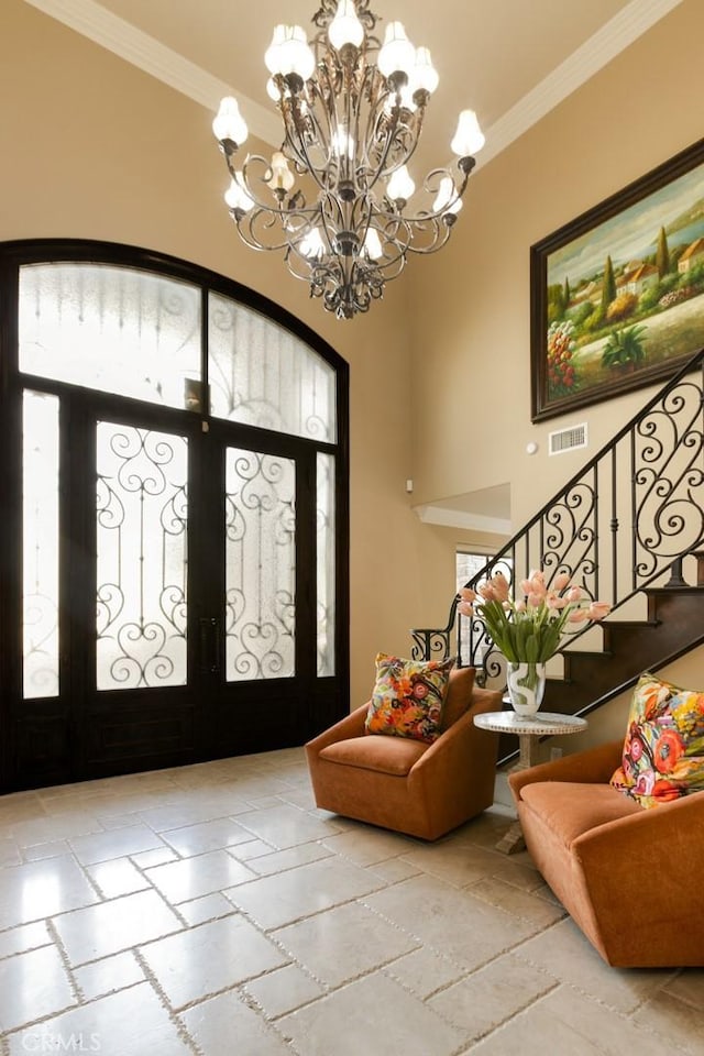 foyer entrance with crown molding, a towering ceiling, and an inviting chandelier