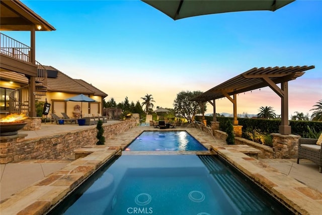 pool at dusk featuring an in ground hot tub, a fire pit, and a patio