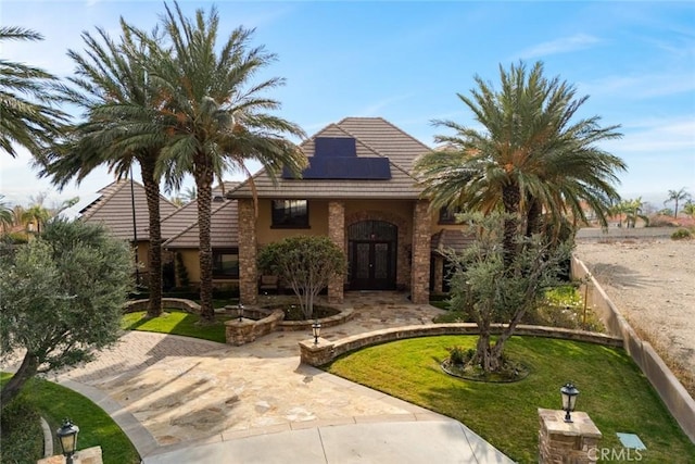 view of front of property with a front lawn and solar panels