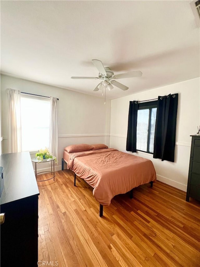 bedroom with multiple windows, ceiling fan, and light hardwood / wood-style flooring