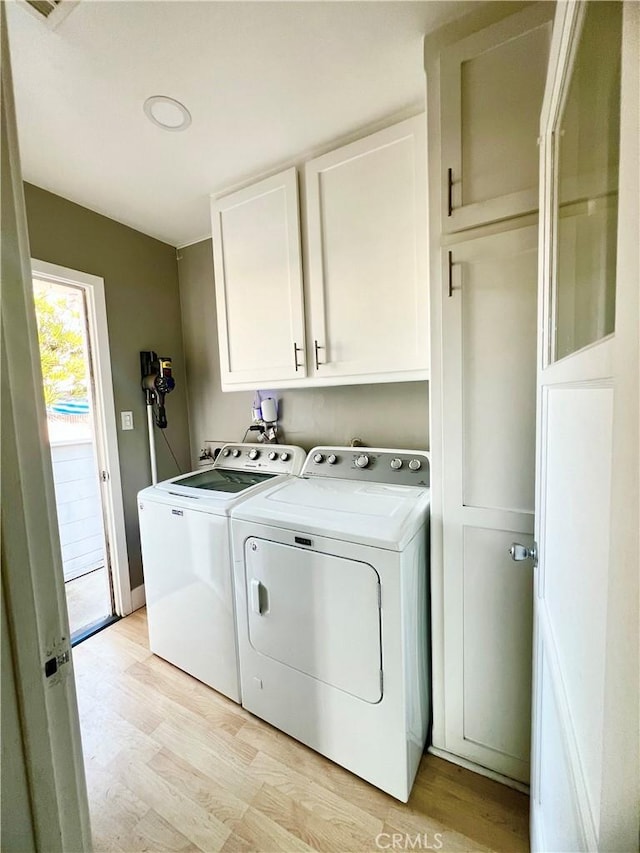 washroom featuring washer and dryer, light hardwood / wood-style floors, and cabinets