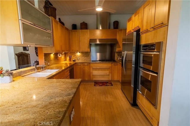 kitchen with sink, stainless steel appliances, light hardwood / wood-style floors, decorative backsplash, and kitchen peninsula