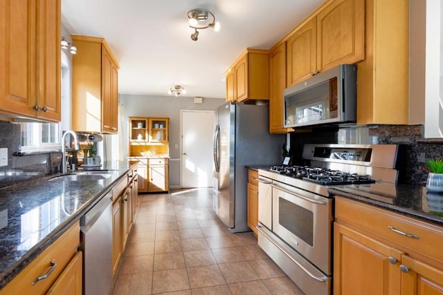 kitchen with light tile patterned flooring, tasteful backsplash, sink, dark stone countertops, and stainless steel appliances