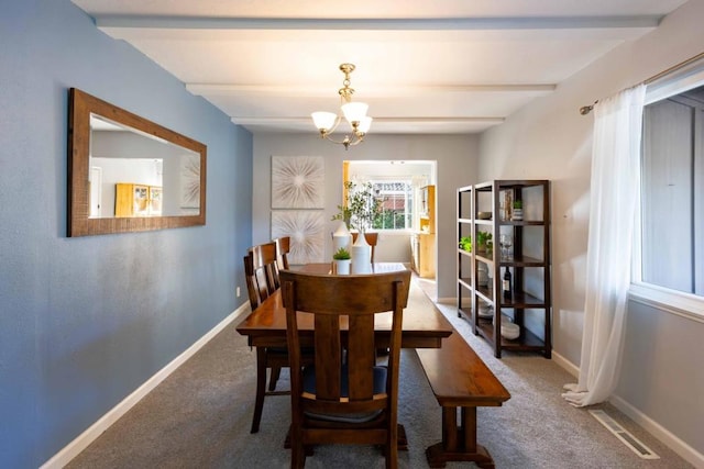 carpeted dining room featuring beamed ceiling and a chandelier