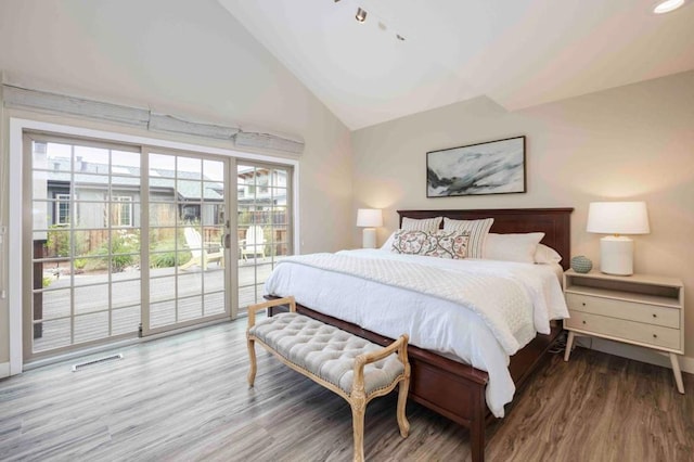 bedroom featuring high vaulted ceiling, access to exterior, hardwood / wood-style floors, and multiple windows