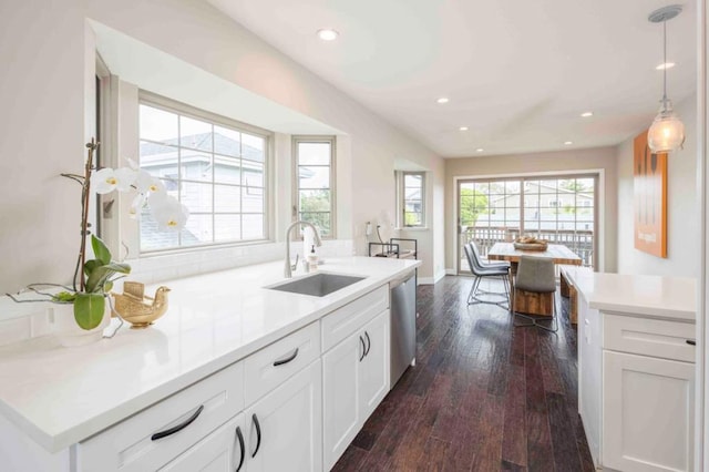 kitchen with dishwasher, white cabinetry, hanging light fixtures, and sink