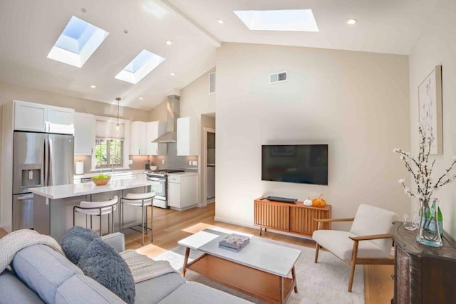 living room with beamed ceiling, high vaulted ceiling, sink, and light hardwood / wood-style floors