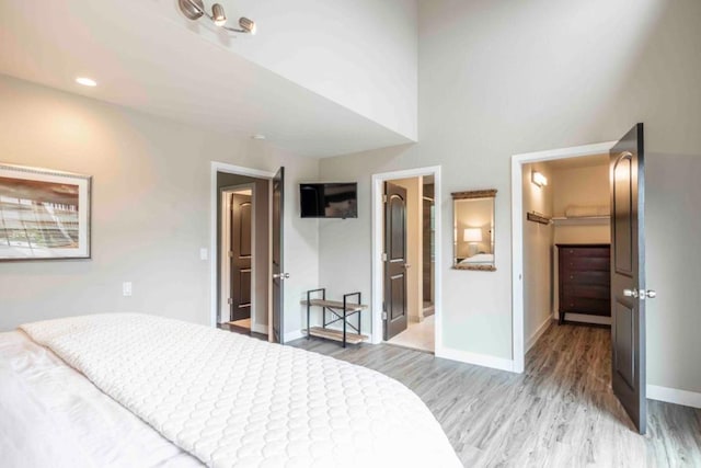 bedroom featuring a closet, a spacious closet, ensuite bath, and light hardwood / wood-style flooring