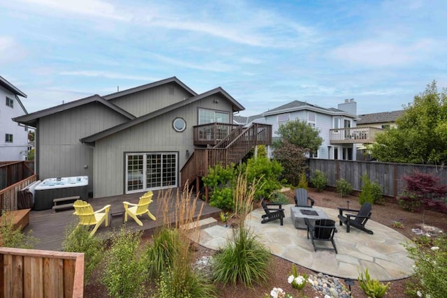 rear view of property with a hot tub, a patio, a deck, and an outdoor fire pit