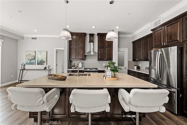 kitchen with sink, decorative light fixtures, wall chimney range hood, and stainless steel fridge with ice dispenser