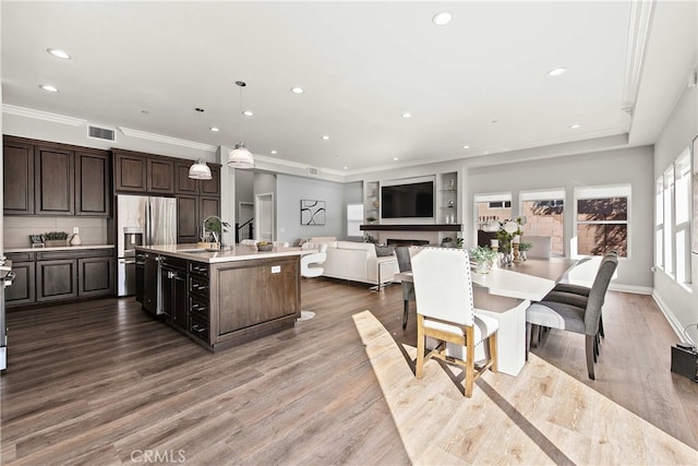 kitchen with sink, a center island with sink, dark brown cabinetry, and decorative light fixtures