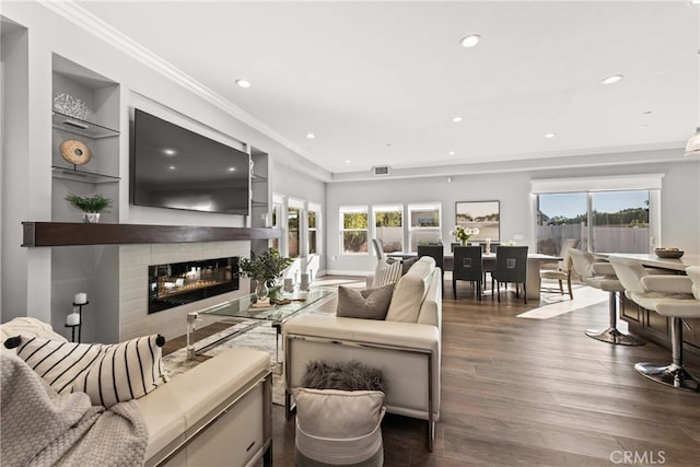 living room with dark hardwood / wood-style flooring, built in shelves, a wealth of natural light, and ornamental molding