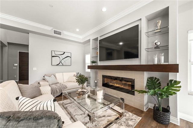 living room featuring dark wood-type flooring, ornamental molding, and built in features