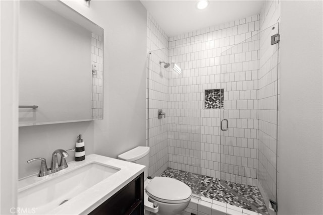 bathroom featuring vanity, a shower with shower door, and toilet